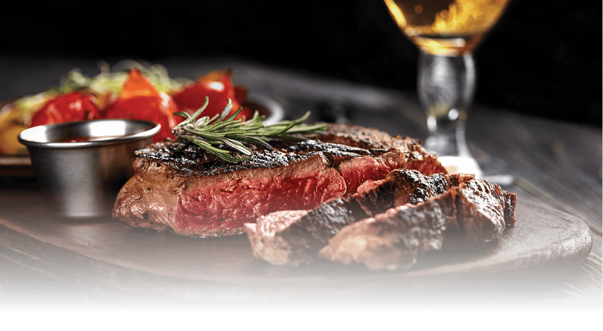 Juicy steak medium rare beef with spices on wooden board on table. dry aged. Served with potatoes, beer, and tomato sauce. Still life