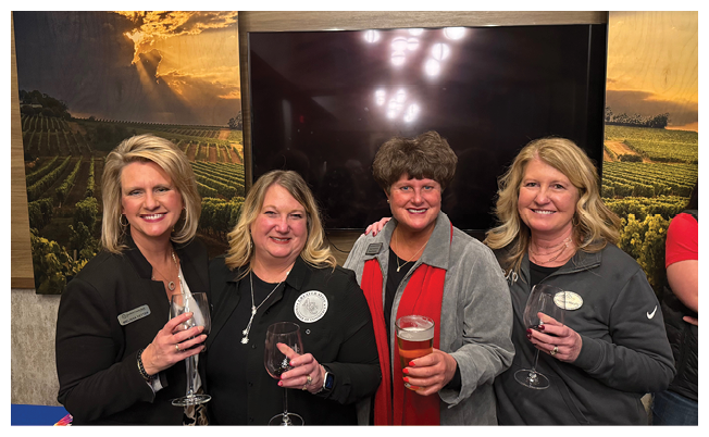 Four women holding wine glasses and beer glasses. Description generated by AI