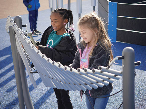 Two young girls play on a playground. Description generated by AI