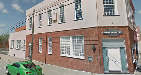 A green car is parked in front of a building. Description generated by AI