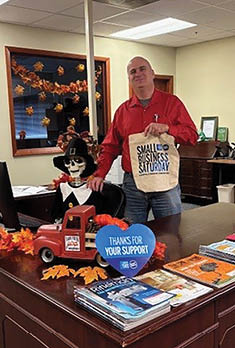 A man is standing in front of a desk with a bag of books on it. AI generated content
