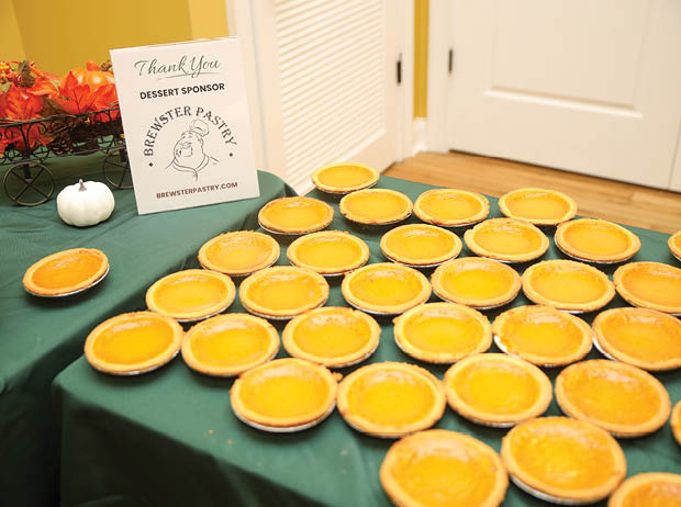 A table with a sign and a bunch of pumpkin pies. AI generated content