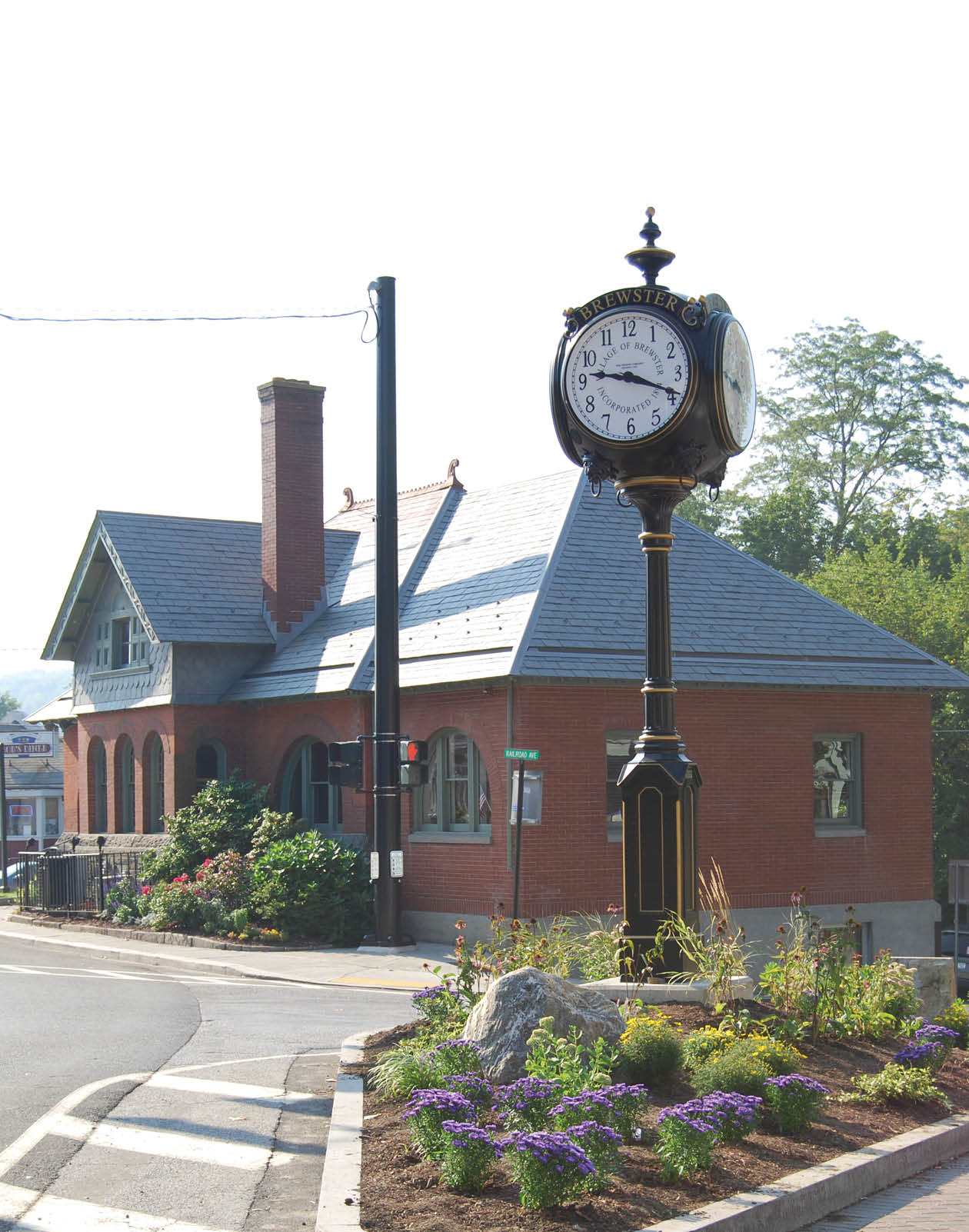 A clock is mounted on a pole in front of a red brick building. AI generated content