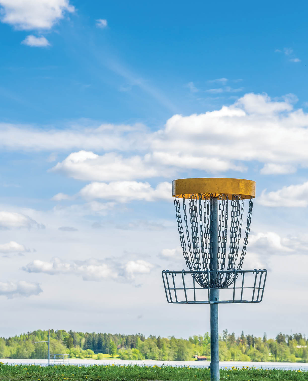 Frisbee golf basket on the grass against beautiful cloudy sky