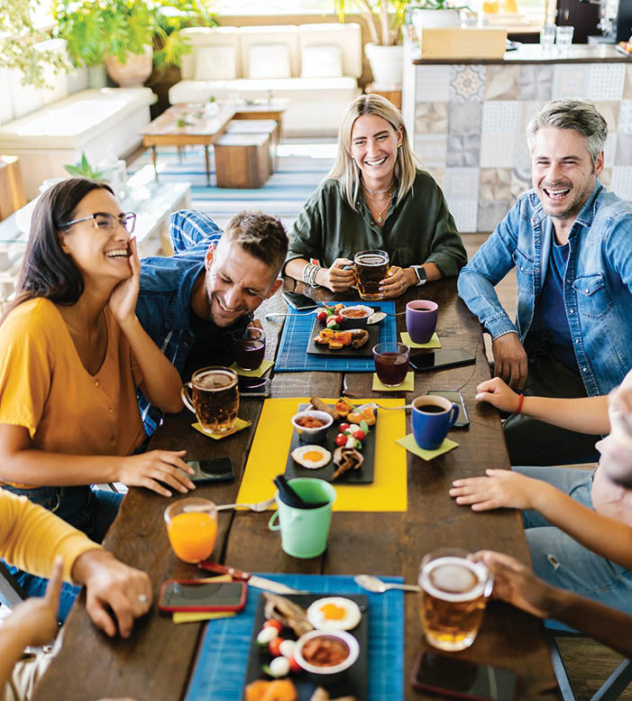 Group of young people having fun drinking on a rooftop terrace of a restaurant - Millennial friends celebrating together while having breakfast - Vertical image