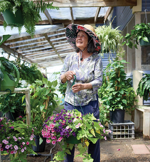 A woman wearing a hat is holding a plant in her hand. AI generated content