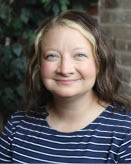 A woman with blonde hair and a blue shirt is smiling for the camera. AI generated content