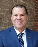 A man wearing a blue suit and a blue tie is smiling for a picture. AI generated content