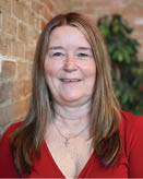 A woman in a red shirt is standing in front of a brick wall. AI generated content