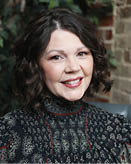 A woman with dark hair and a black shirt is smiling. AI generated content