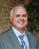 A man wearing a suit and tie is smiling for the camera. AI generated content