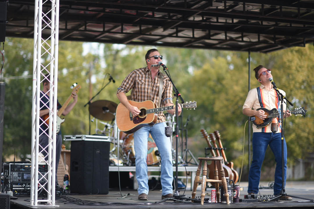 Three men are playing guitars on stage in front of a crowd. AI generated content