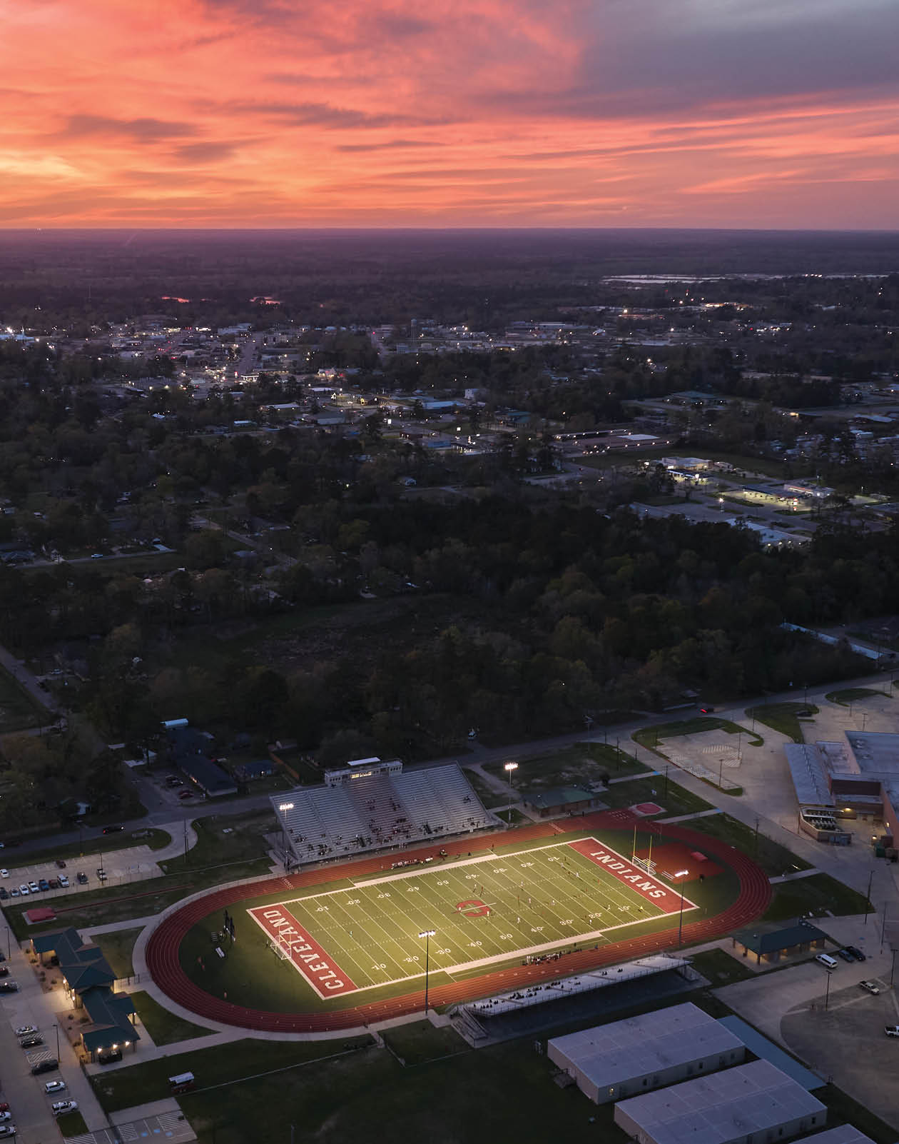 A cityscape at sunset with a football field in the foreground. AI generated content