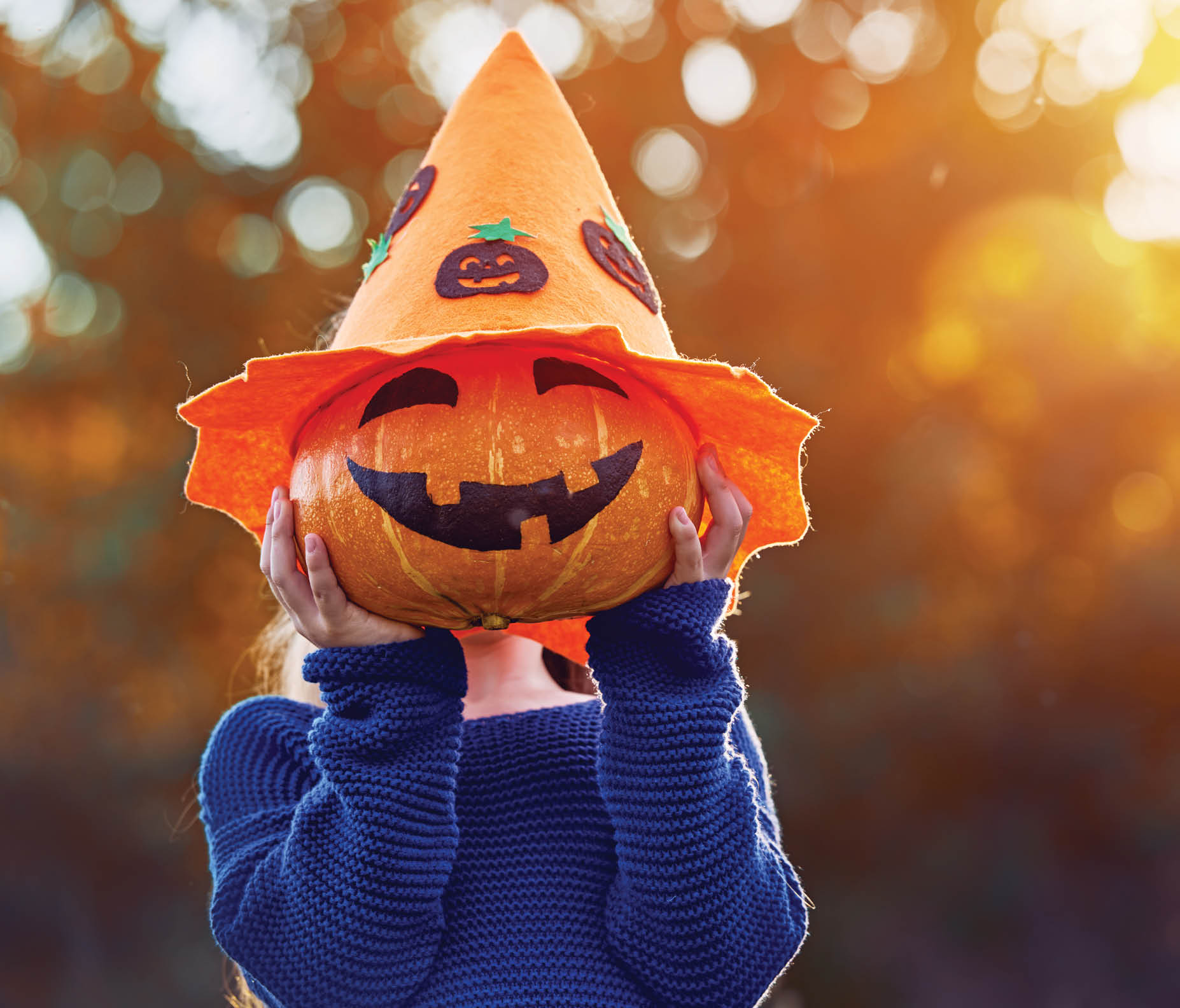Happy Halloween! Cute little child with a pumpkin in the park.