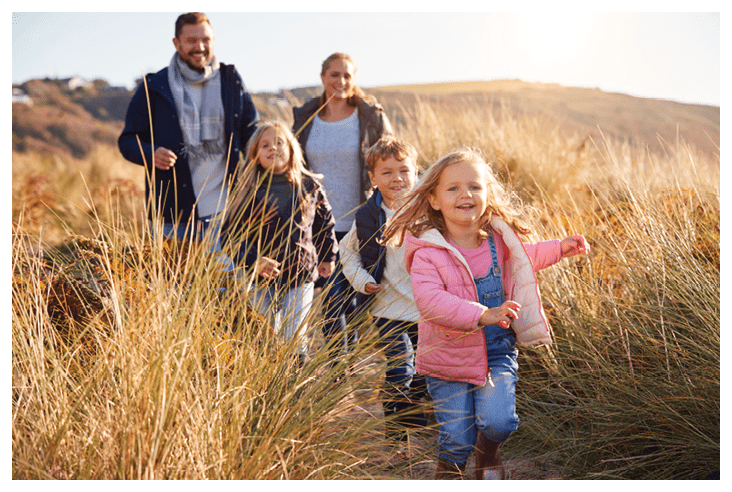 Family Walking Along Path Through Sand Dunes Together