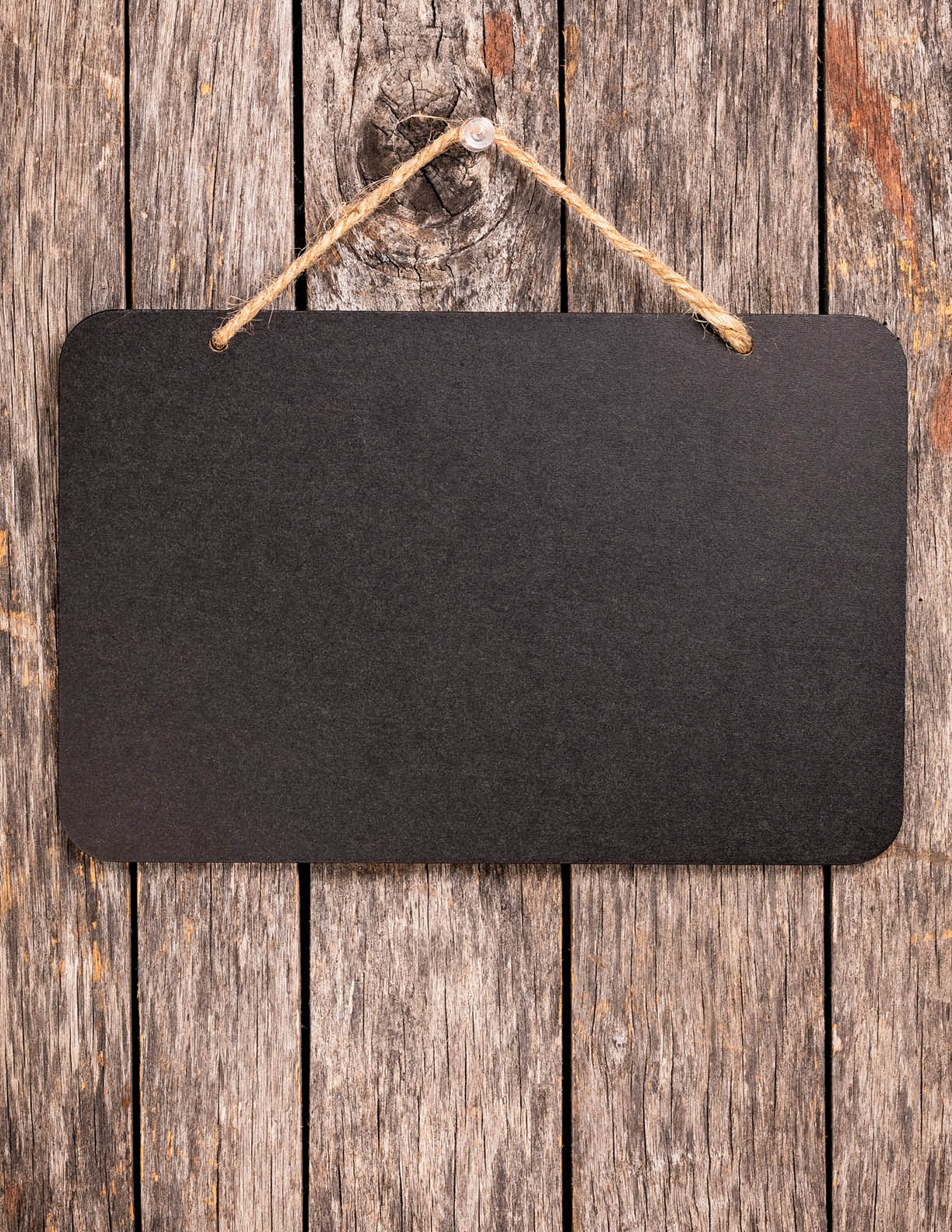 Blank chalkboard sign hanging from old wooden background.