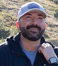 A man wearing a hat and a black jacket is smiling. AI generated content