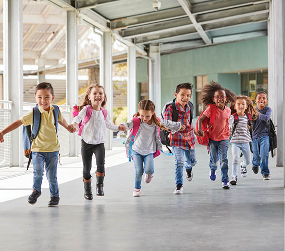 Primary school kids run holding hands in corridor, close up
