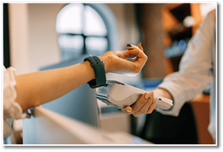 Female using a green smart watch, paying over him, putting it close to the paying machine.