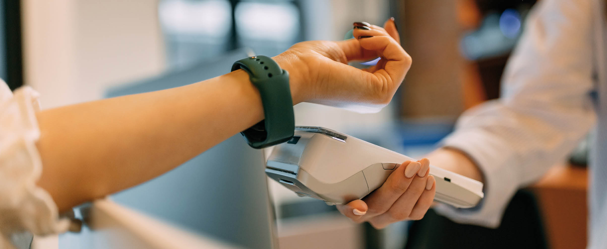 Female using a green smart watch, paying over him, putting it close to the paying machine.