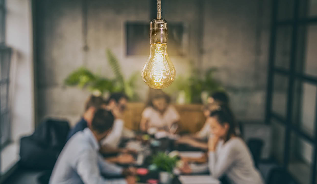 Young business people are discussing together a new startup project. A glowing light bulb as a new idea.