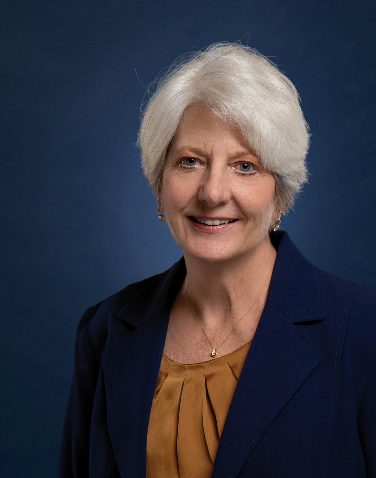 A woman wearing a blue jacket and an orange shirt is smiling for the camera. AI generated content