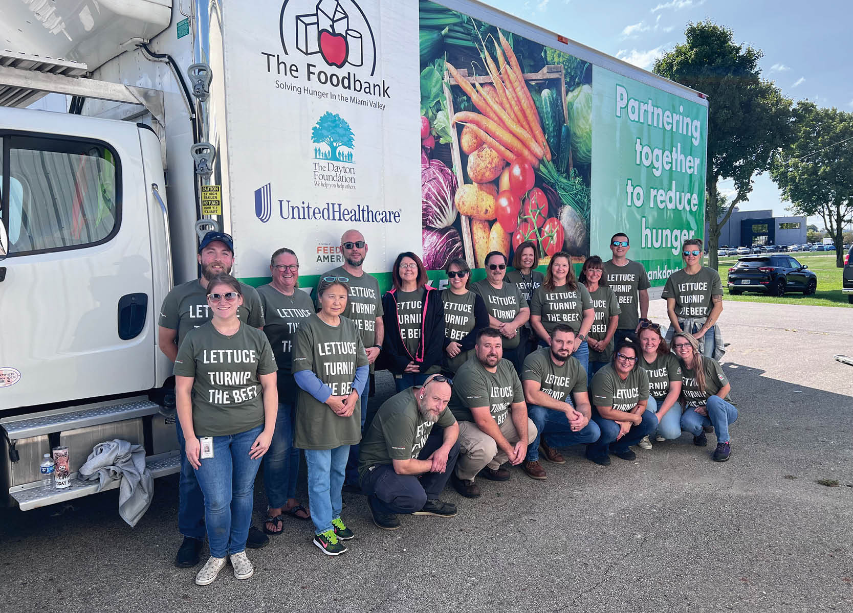 A group of people wearing green shirts pose in front of a truck. AI generated content