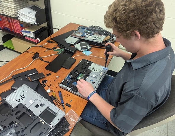 A man is working on a laptop computer, which is placed on a wooden table. AI generated content