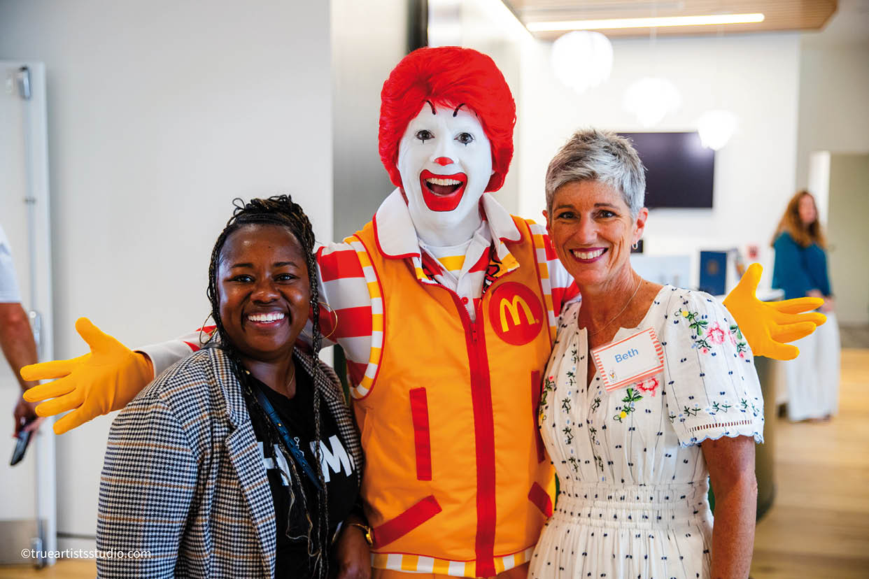 A woman and a man are standing next to a Ronald McDonald mascot. Description generated by AI