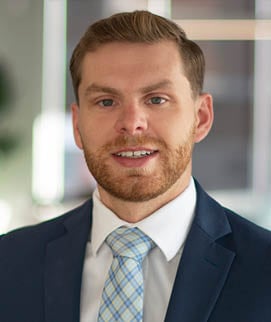 A man wearing a blue suit and a blue and white tie. Description generated by AI