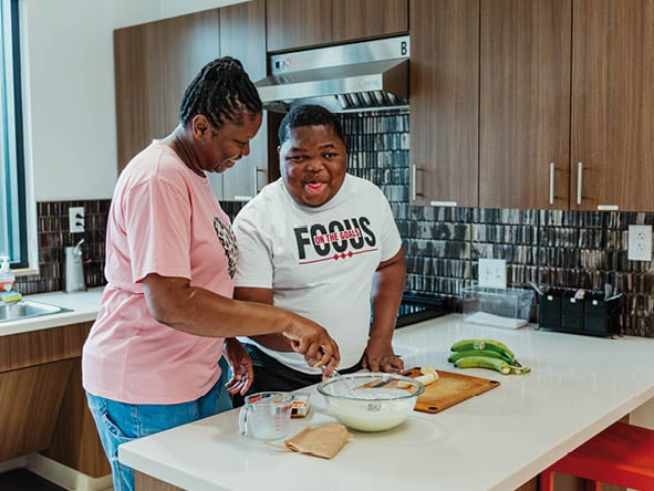 Two women standing in a kitchen. Description generated by AI