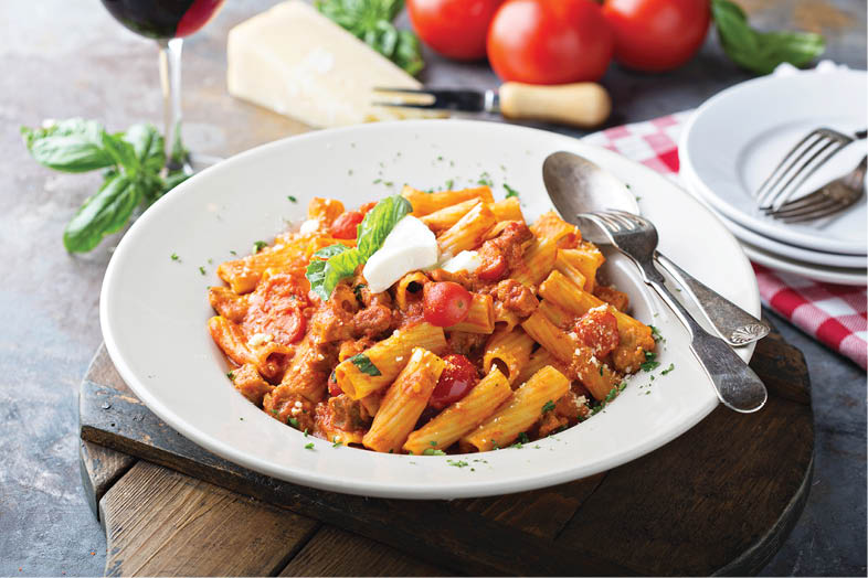 Rigatoni bolognese with fresh mozarella and basil in a big plate