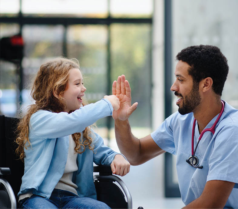 Young multiracial doctor having fun with little girl on a wheelchair.