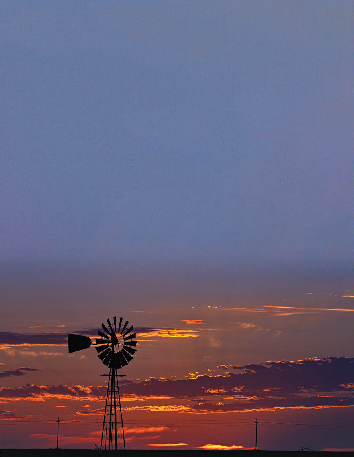 A windmill with a red and white striped sail is silhouetted against a beautiful sunset. AI generated content