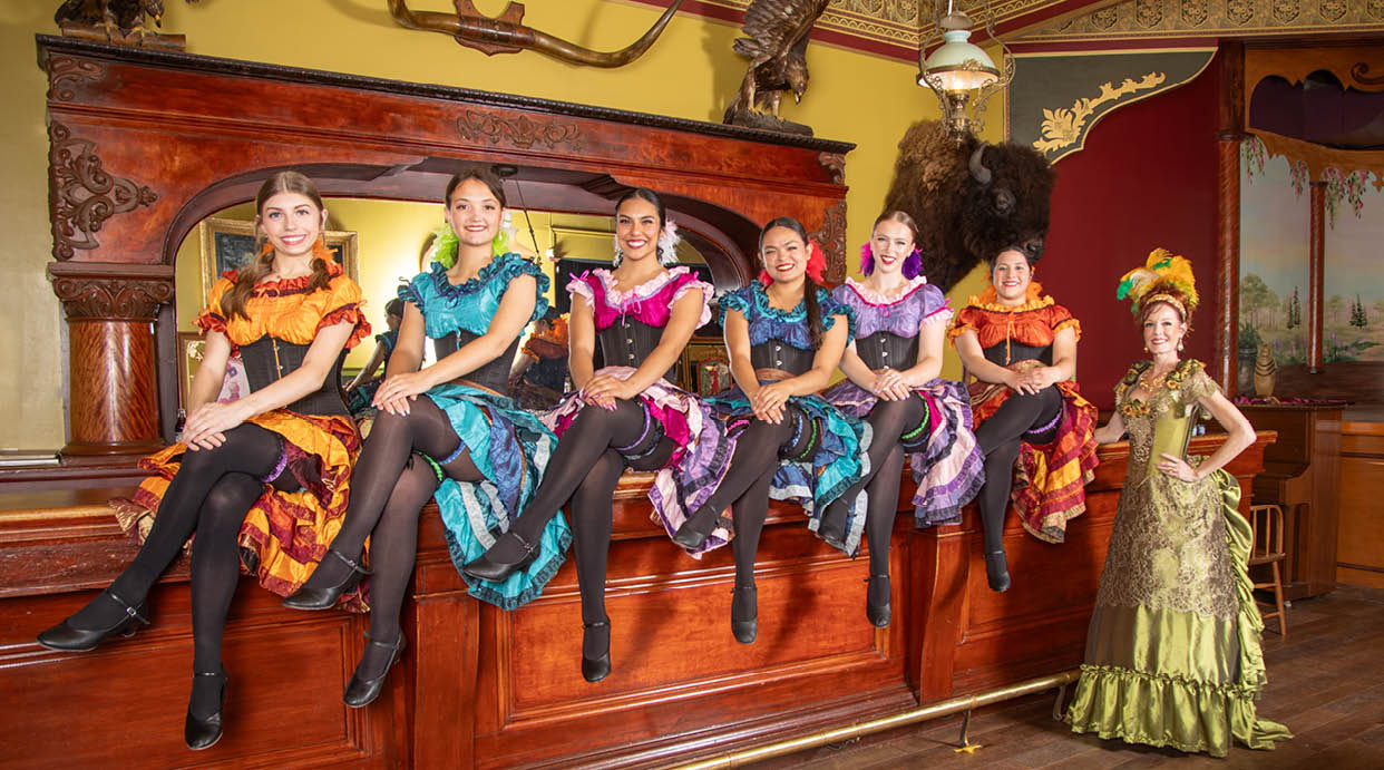 A group of women are sitting on a bench, wearing colorful dresses. AI generated content