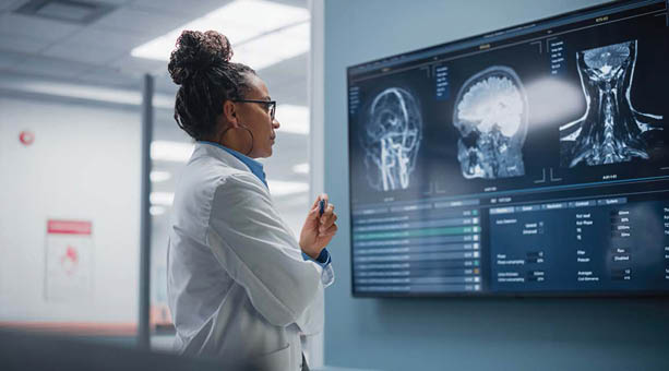 A woman in a white lab coat is looking at a computer screen displaying a brain scan. AI generated content