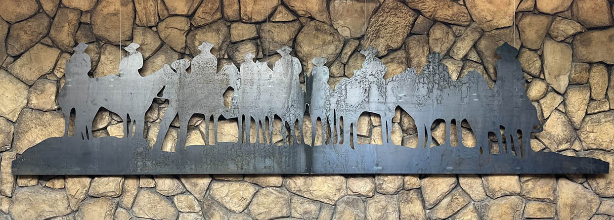 A sculpture of a group of people is displayed on a stone wall. AI generated content
