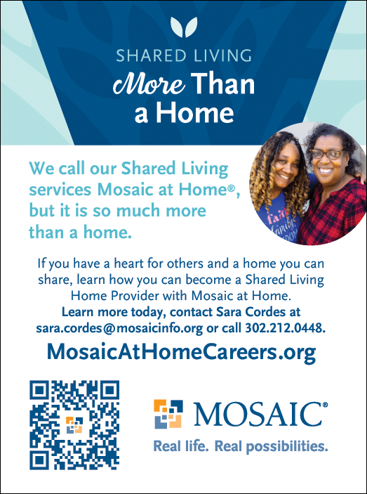 Two women are smiling for a photo, one of them is wearing a blue shirt. They are standing in front of a sign that says “Shared Living More than a Home". AI generated content
