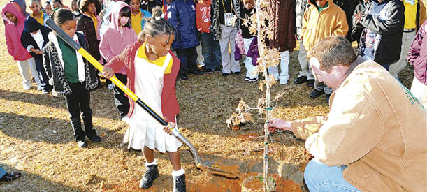 ARBOR DAY---Even though Friday is Arbor Day, the kindegarten classes of Susie Dasher with help from the City of Dublin Tree Board celebrated a day early by planting five oak trees on their school's campus Thursday. Above Susie Dasher student Moani Johnson was first in line to shovel dirt around a tree as Rodney Soles,Tree Board Chairman holds the oak straight.  The live and shumard oaks were supplied by the school and the City of Dublin Tree Board.