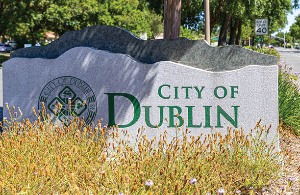 A sign for Dublin is located on a sidewalk. AI generated content