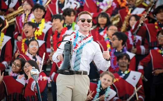 A man in a white shirt and tan pants is holding a trombone in front of a crowd of people. AI generated content