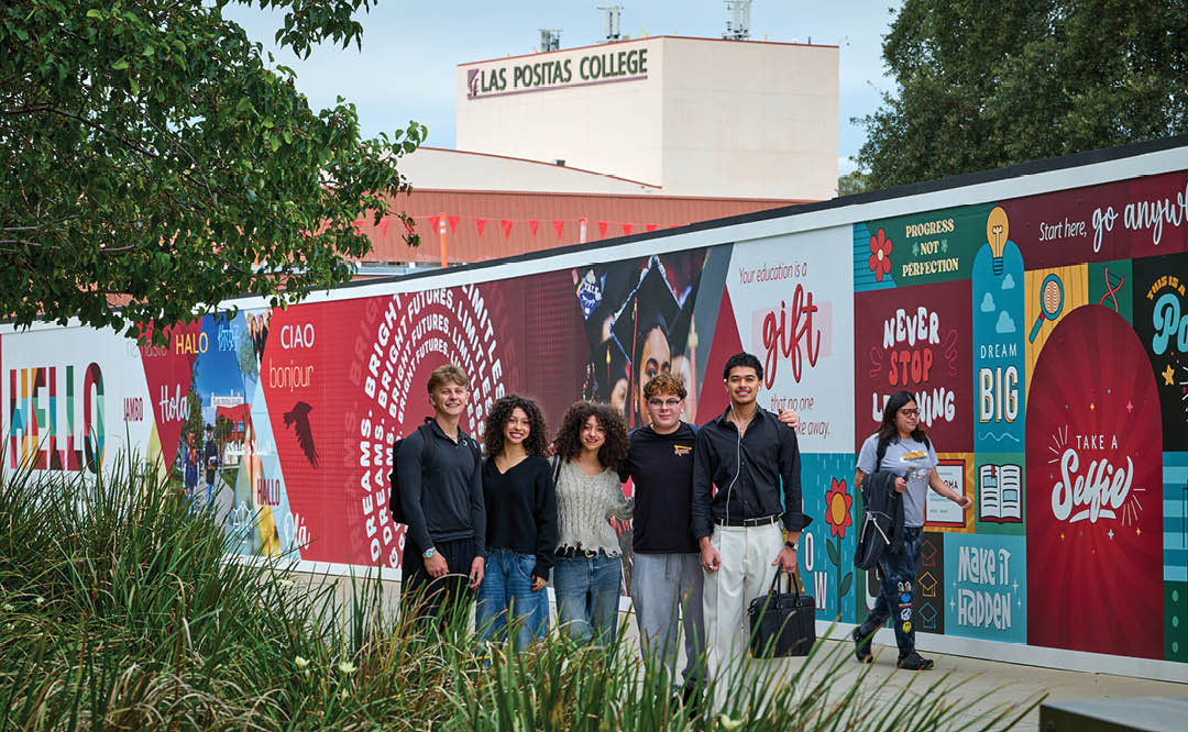 A group of five people pose for a picture in front of a wall with advertisements. AI generated content