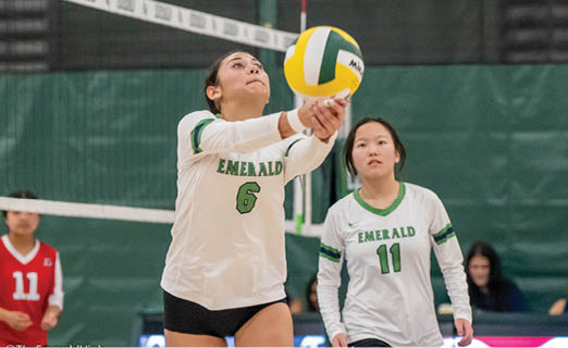 A woman in a white shirt and black shorts is playing volleyball. She is reaching up to hit the ball with her hand. Another woman is watching her play. AI generated content