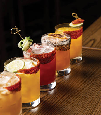 Four glasses of mixed drinks are lined up on a table. AI generated content