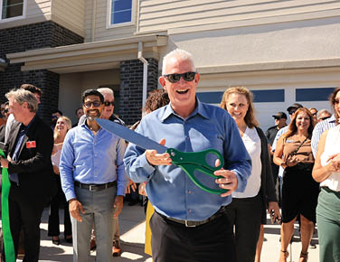 A man is holding a pair of scissors and cutting a ribbon in front of a crowd of people. AI generated content