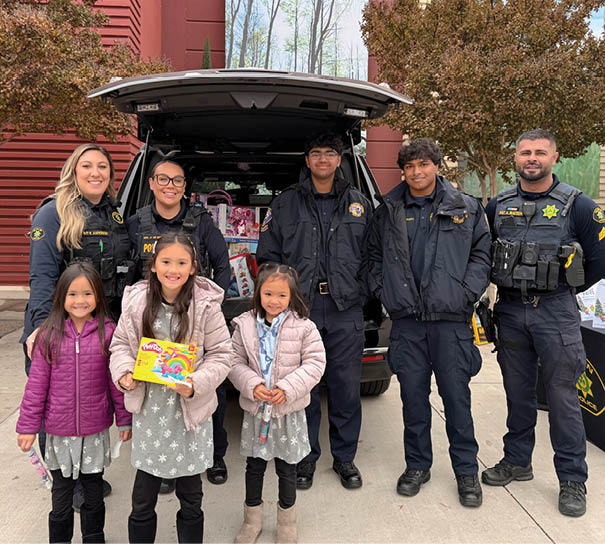 A group of people, including children, pose with police officers in front of a car. AI generated content