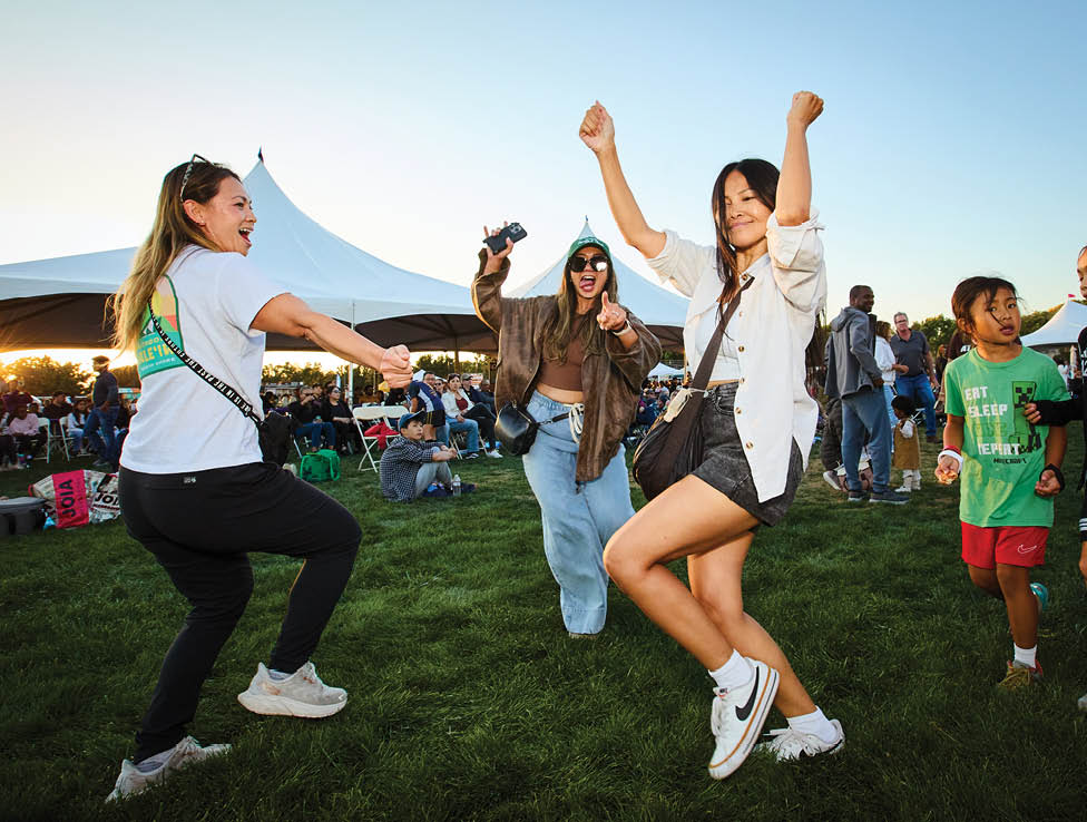 A group of people are standing in a field, with some of them dancing and others taking pictures. AI generated content