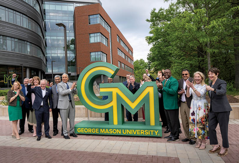 President Gregory Washington, Dean Ajay Vinz , and Donald G. Costello College of Business faculty and supporters pose with the new George Mason University logo display on the Roger Wilkins Plaza on the Fairfax Campus. Photo by Evan Cantwell/Creative Services/George Mason University