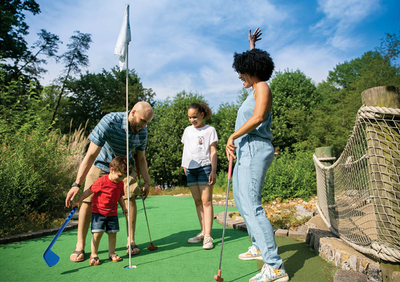 A man, woman, and child are playing miniature golf. Description generated by AI