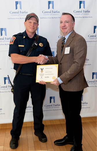 A man in a police uniform is shaking hands with another man. Description generated by AI